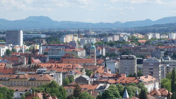 Pogled s Kalvarije na Maribor s stanovanjskimi bloki, rdečimi strehami in Pohorjem v ozadju